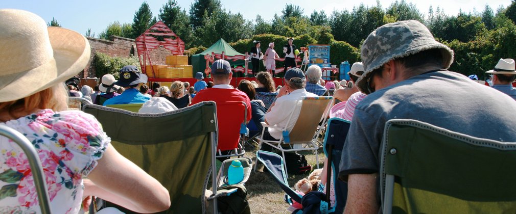 People sat outside watching an outdoor theatre show