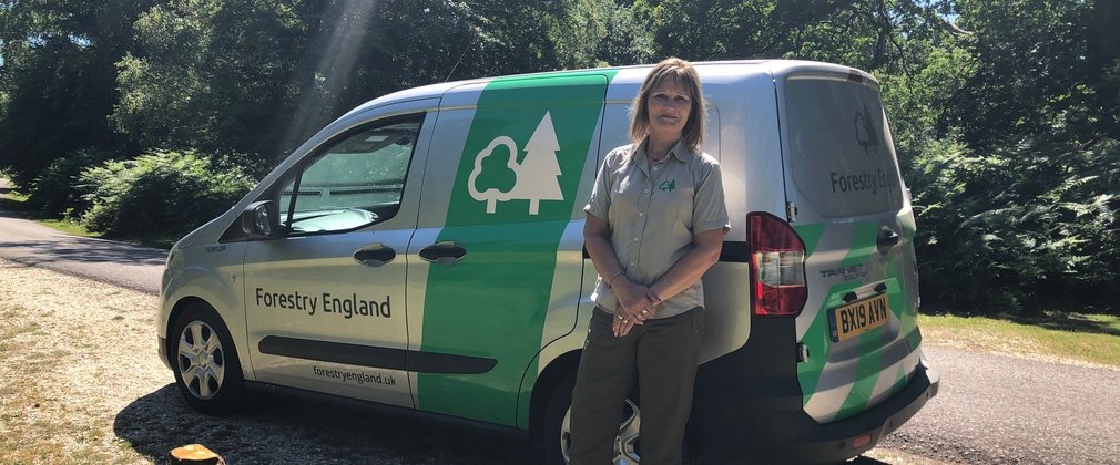 Forestry England staff member stood next to van on sunny day