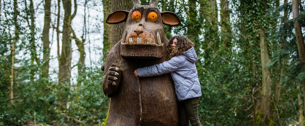 Young girl hugging the Gruffalo Sculpture at Westonbirt 