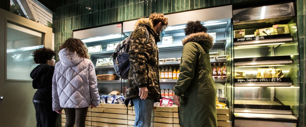 A family gaze into an open refrigerator full of drinks and sandwiches
