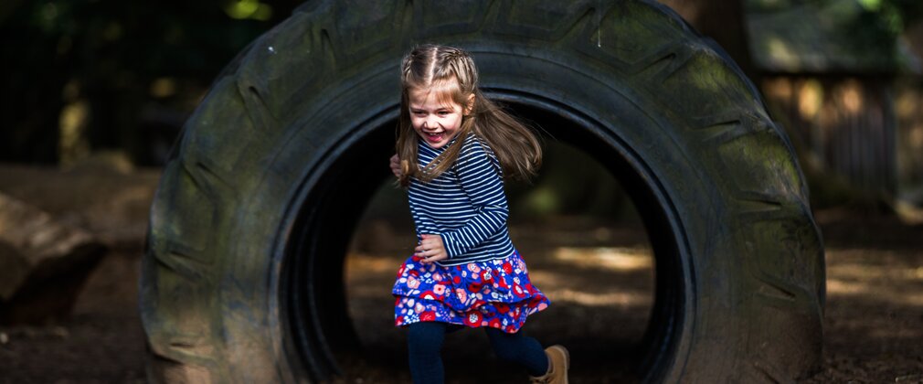 A little girls runs through a large tyre tunnel