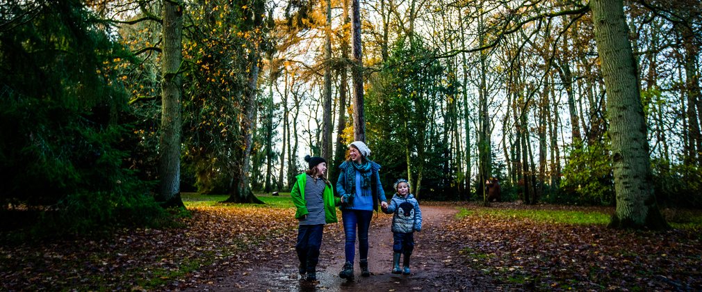 Mother with young boy and girl walk hand in hand down a winter path