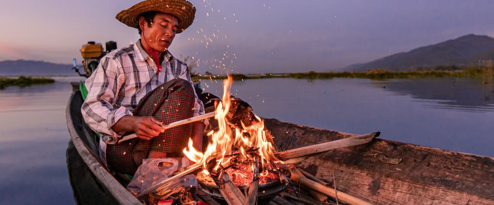 Earth Photo shortlisted work - photo of man creating a fire on a boat on a lake