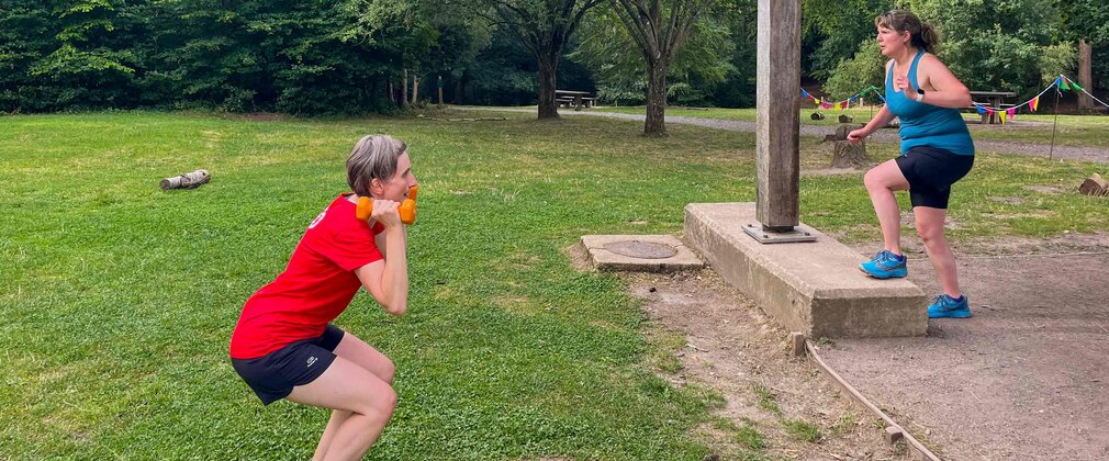 Two people training outside in a forest park setting.