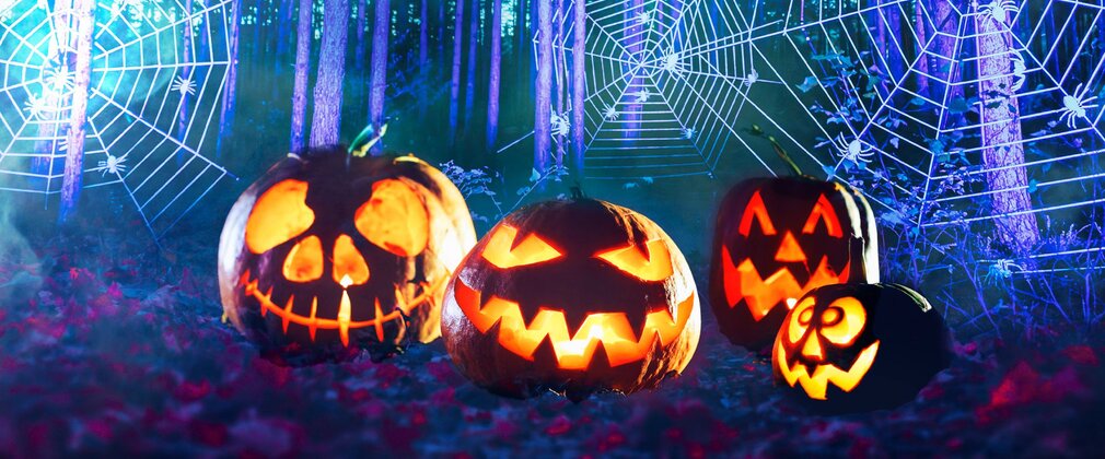 Four pumpkins carved into faces shown in an eerie forest