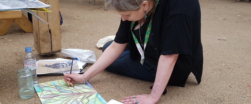 Lady sat on the ground drawing a tree