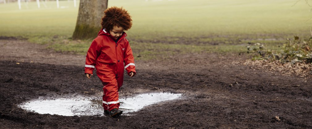 Child walking through a puddle in orange rain wear