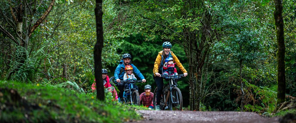 Family cycling on a trail surrounded by woodland 