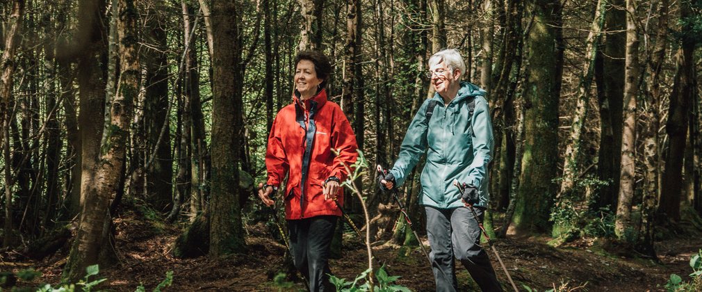 Two women Nordic walking with poles in the forest