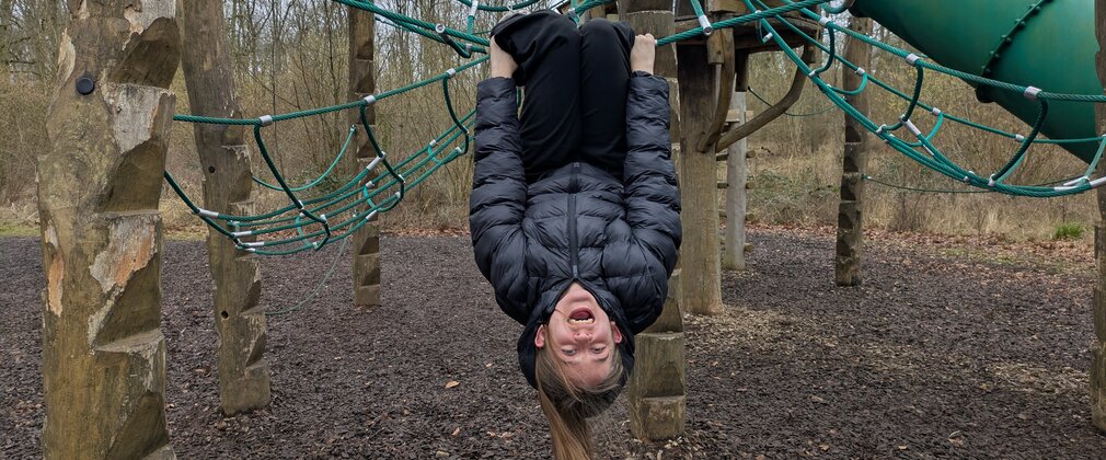 A child hanging upside down on a play area