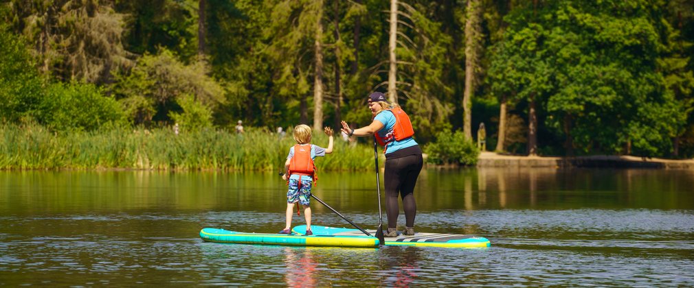 Lady giving child a high five whilst both on paddleboards