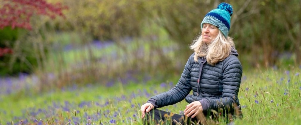 Person sitting amongst bluebells meditating