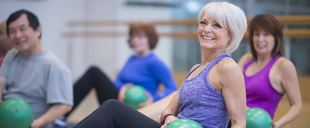 A group of older adults doing pilates with weighted balls