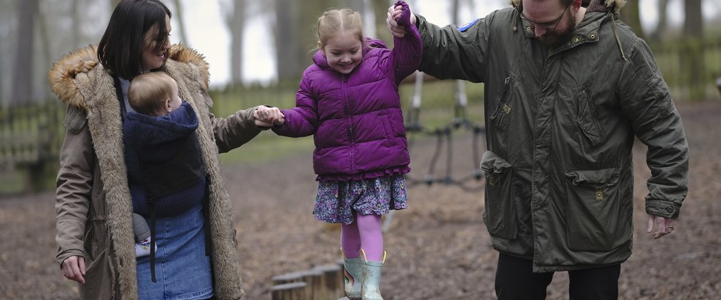 girl balancing on wooden beam in play area in the forest 