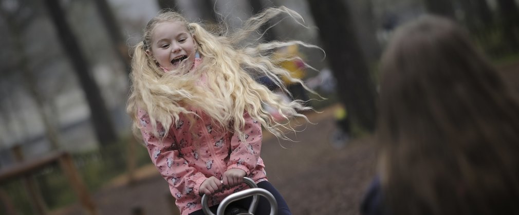 girl playing on a see-saw in the forest