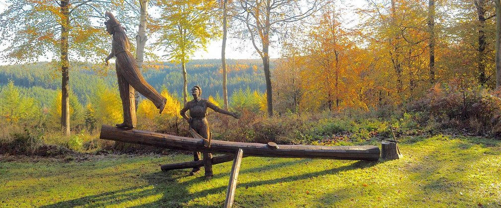 A rusted metal sculpture of two female foresters working on a tree.