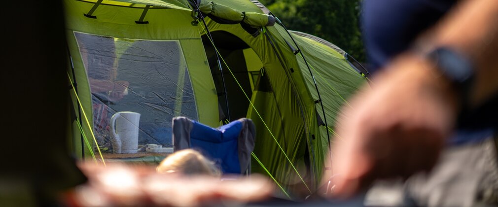 Man cooking next to a green tent at Rendlesham campsite