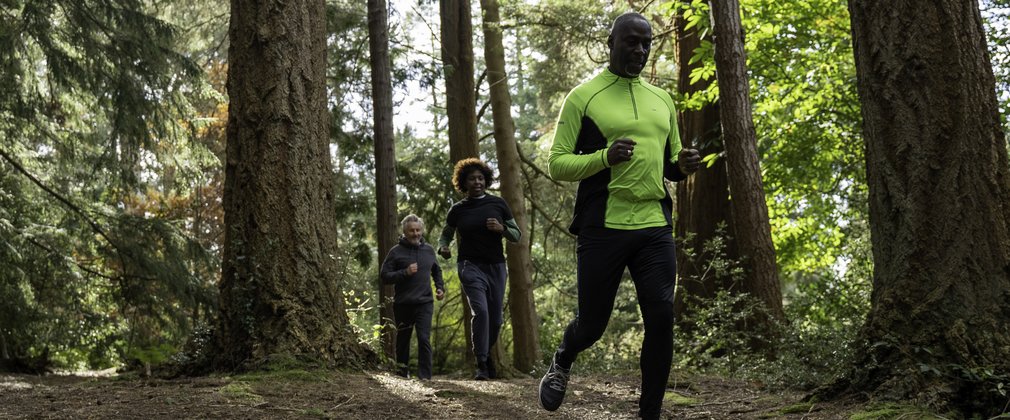 three people running in forest