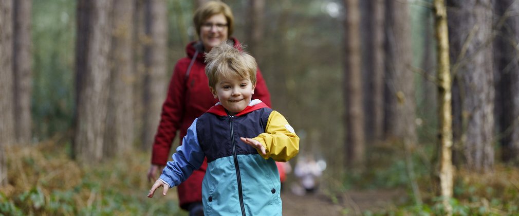 Young boy and older woman walking through the forest