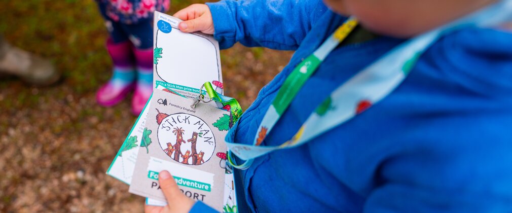 Child in blue jumper examining a lanyard with Stick Man branded cards.