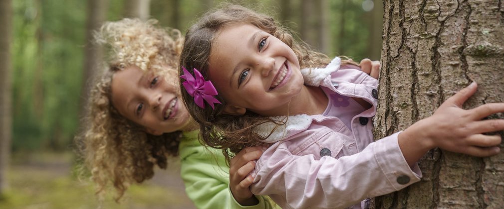 Two children hugging a tree at Salcey Forest