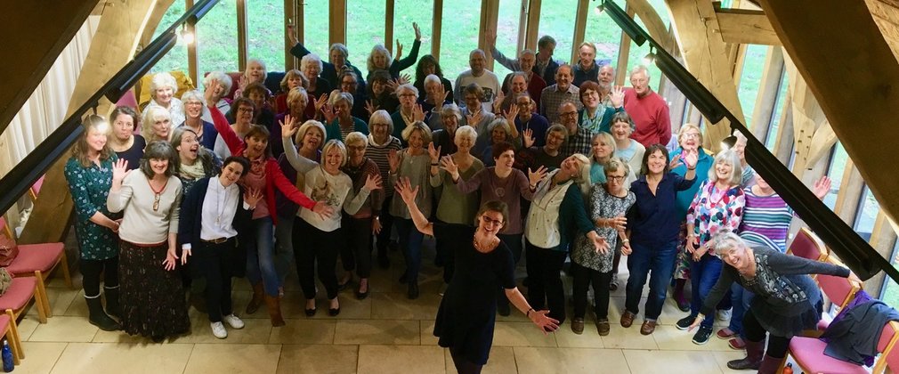 A group of singers participating in a singing workshop in an oak framed hall
