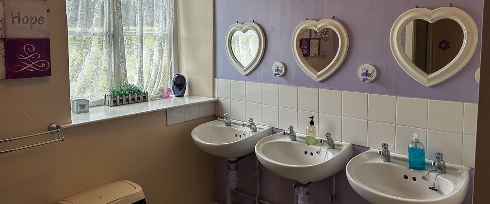 Three sinks in a bathroom with a lilac wall
