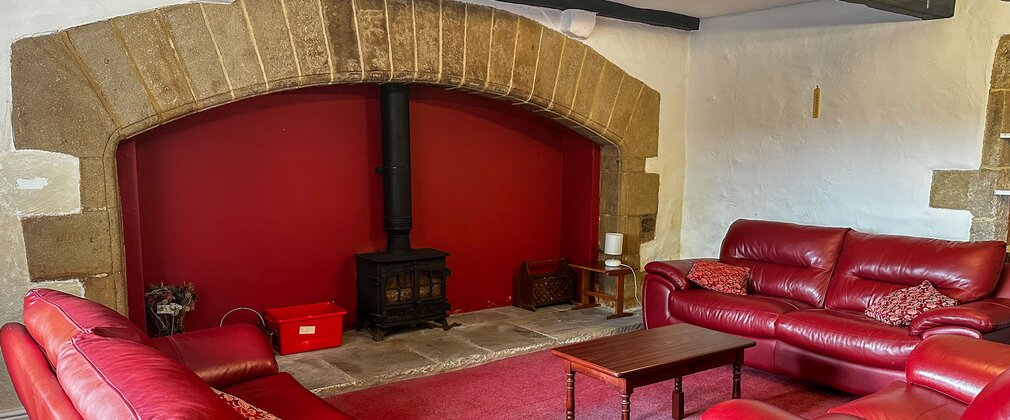A red three piece suite centred around a log burner
