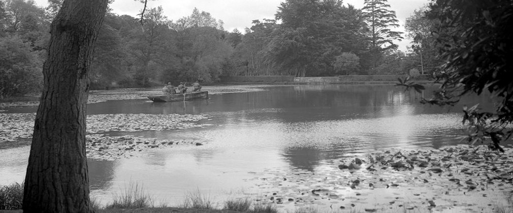 black a white photo of a lake with a rowing boat