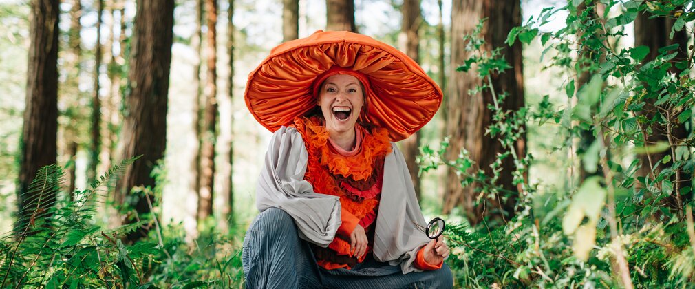 A woman dressed as a mushroom crouched among the trees 