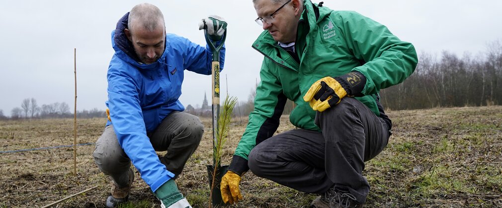 two men with a spade looking at soil