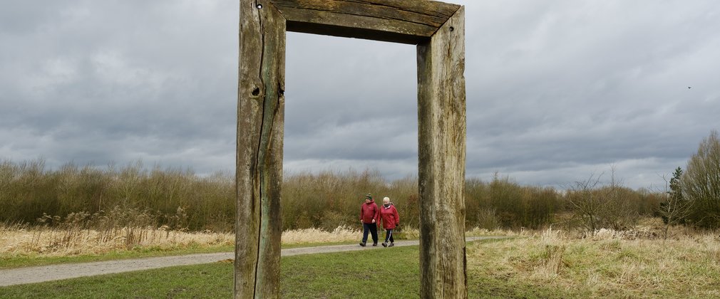 A couple walking by the side of a art installation at Viridor Woods