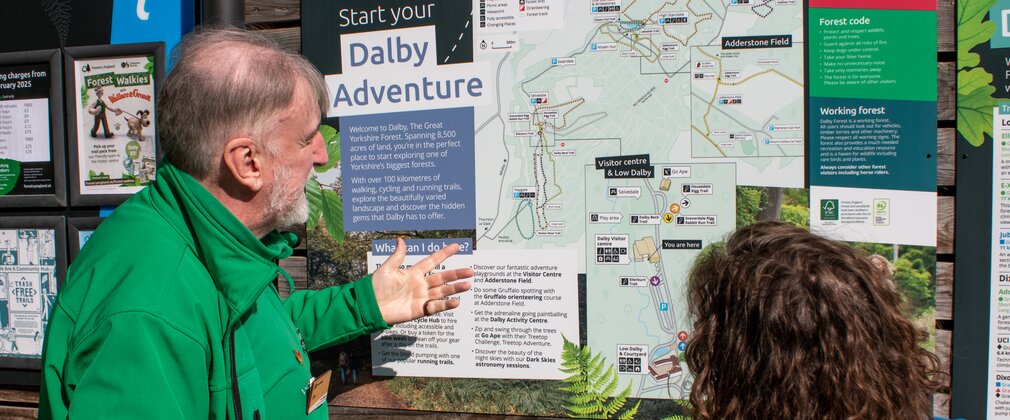 A volunteer showing a visitor a map of walking trails