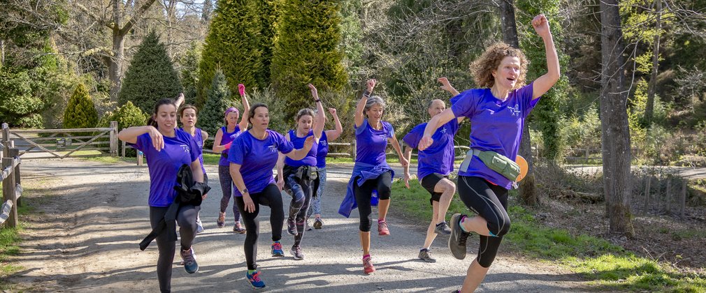 Group of runners in forest jumping in the air