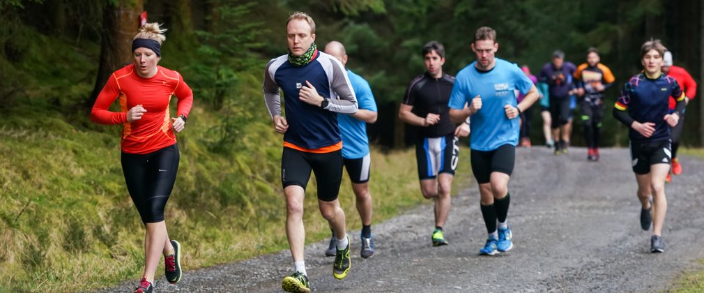 Adults running along forest path 