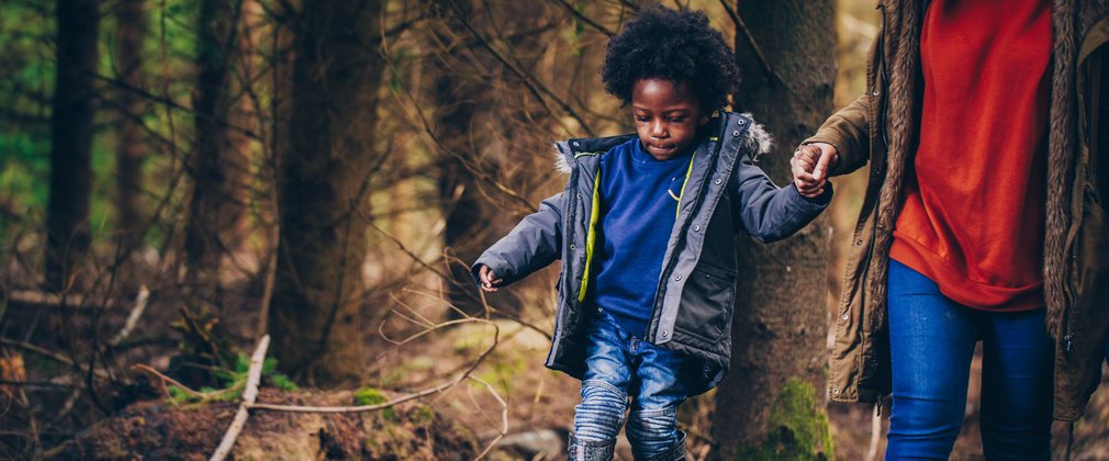 Kid walking along trunk log holding parent's hand