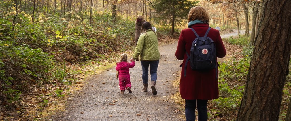 Mother and child walking on forest path during autumn