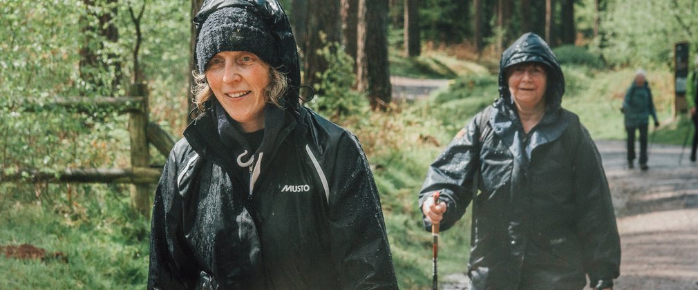 two women nordic walking with raincoats in a forest