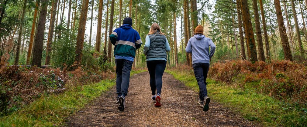 Three people running in a forest