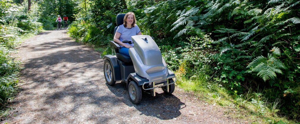 A person exploring the forest on an all-terrain mobility scooter