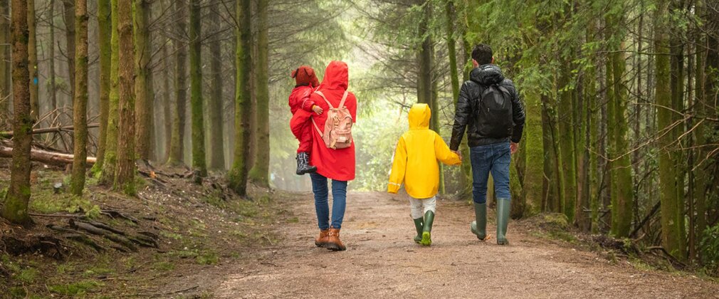 Two adults and two children walking on a forest path in winter.