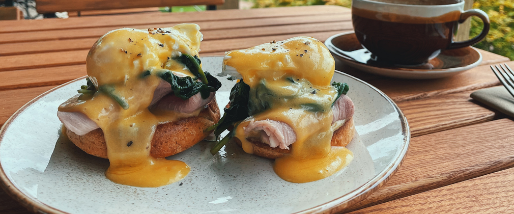 A plate holding Toasted English muffin, poached eggs, buttered spinach & hollandaise