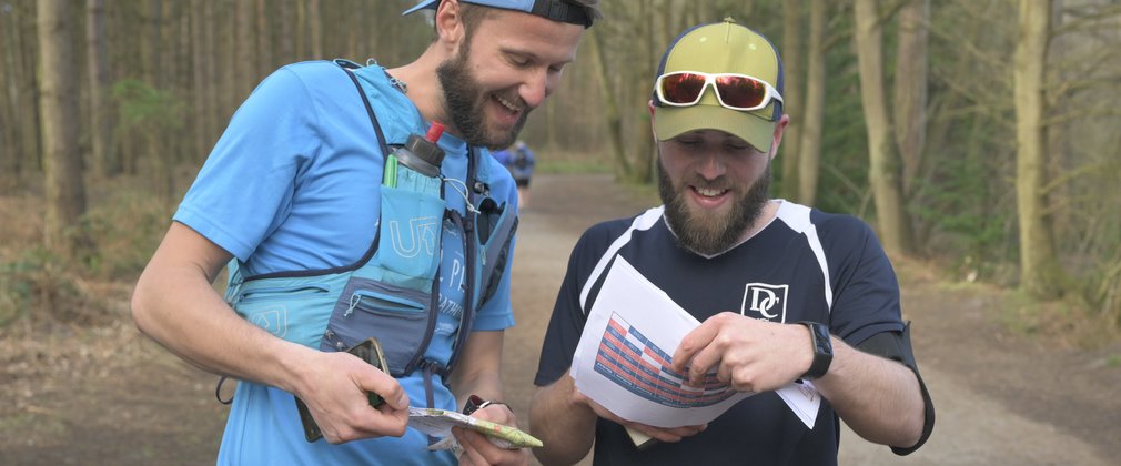 two men looking at a map in a forest