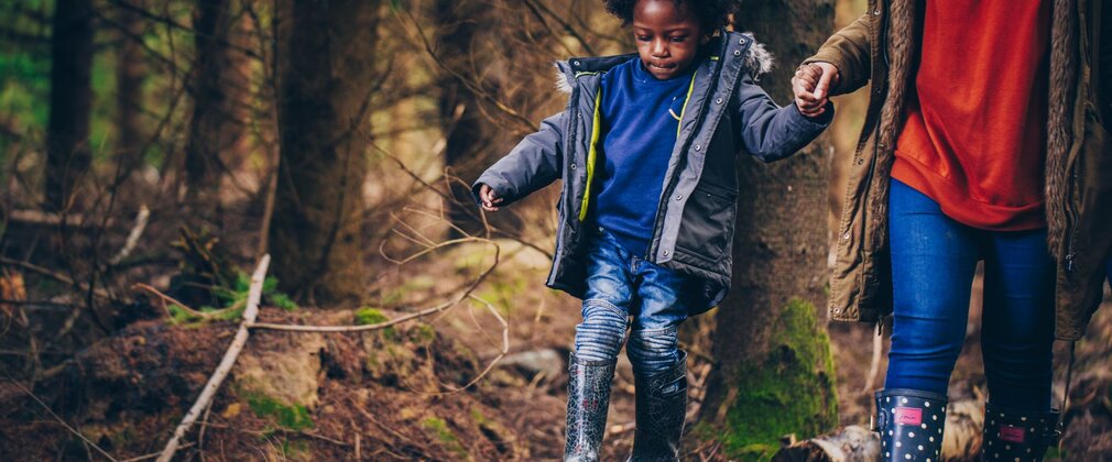Kid walking along trunk log holding parent's hand