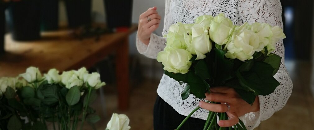 A woman holds a bouquet of white roses.