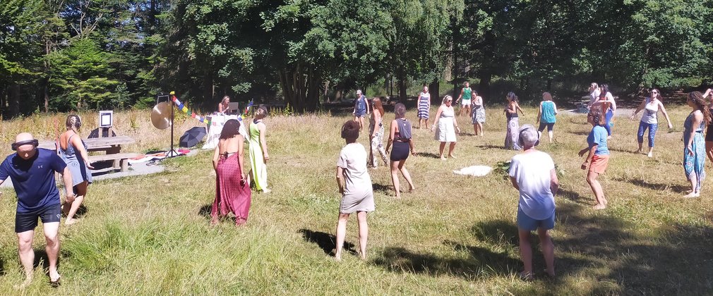 A group of people dancing in a forest clearing.