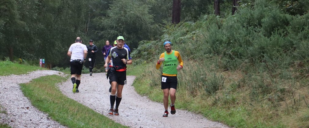 Participants taking part in a running event within a forest setting.