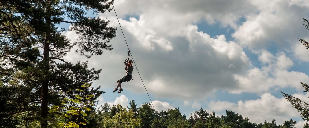 Person on a zip wire, high ropes course in the forest