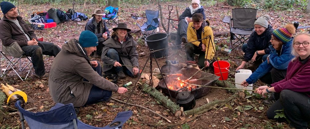 Group sat around a fire under canvas