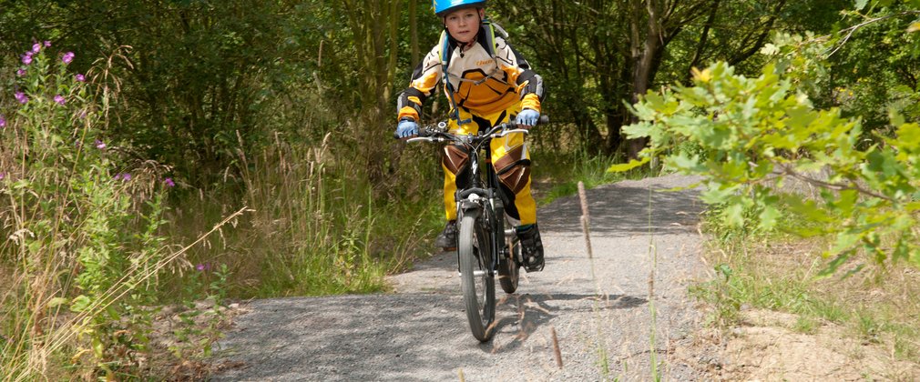 Child mountain biking on forest track